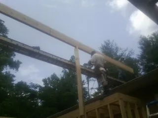 Carpenter setting a ridge beam over a new addition frame — Ice Dam Removal by Roofing Brothers in Whitestown