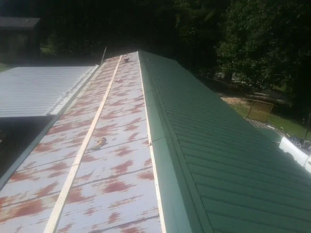 Old rusted panels beside newly installed green metal roofing — Wind Damage Roof Repair by Roofing Brothers in Whitestown