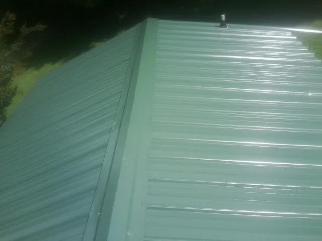 New green metal panels meeting at the ridge of a roof — Flat Roof Repair work by our crew in Whitestown