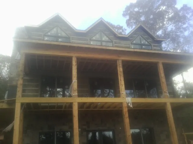 Dormers and porch framing on a large log home under construction — Roof Coating work by our crew in Whitestown