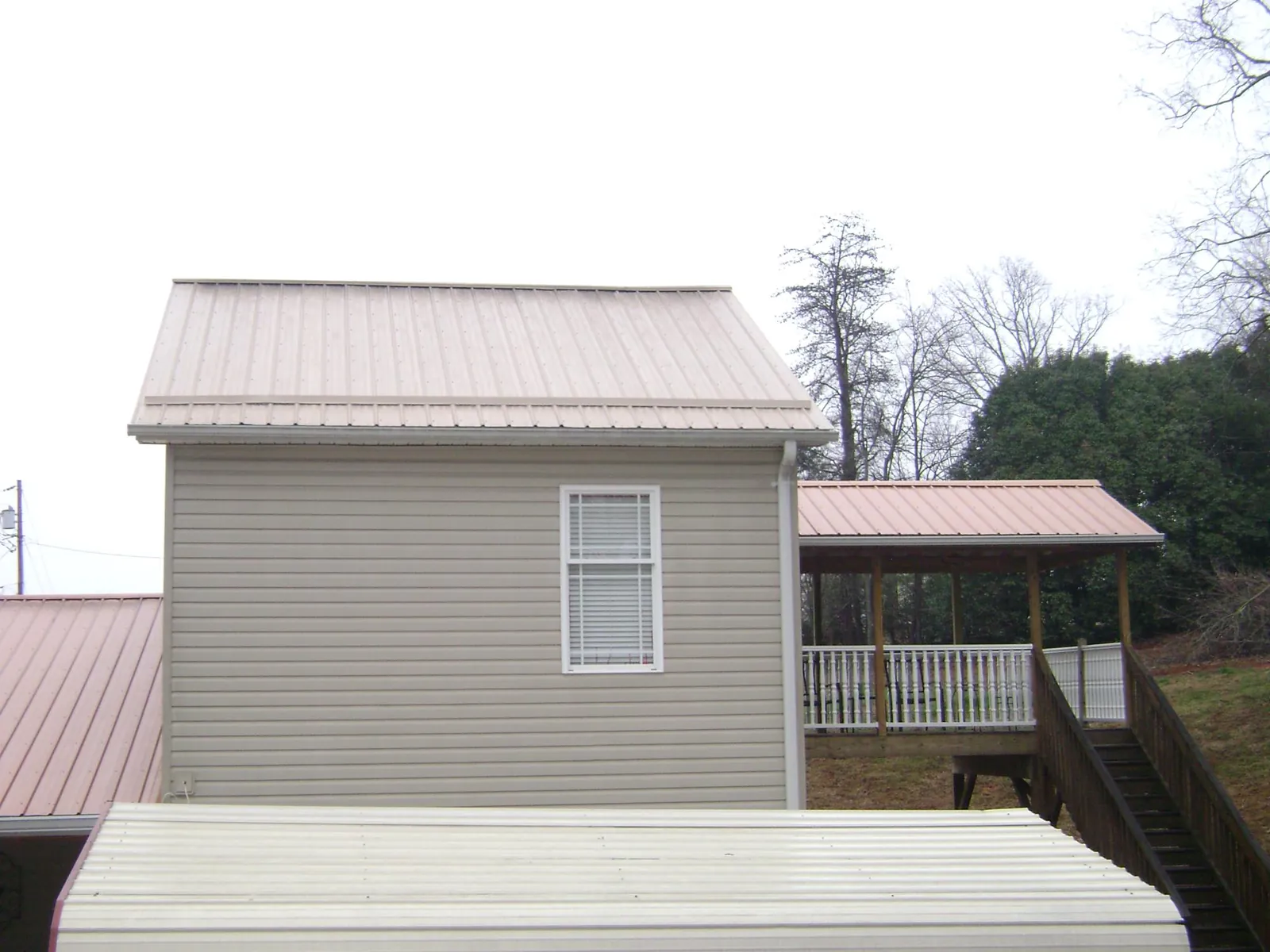 Tan metal roofs on a two story addition and attached porch, from a Roof Replacement job in Whitestown
