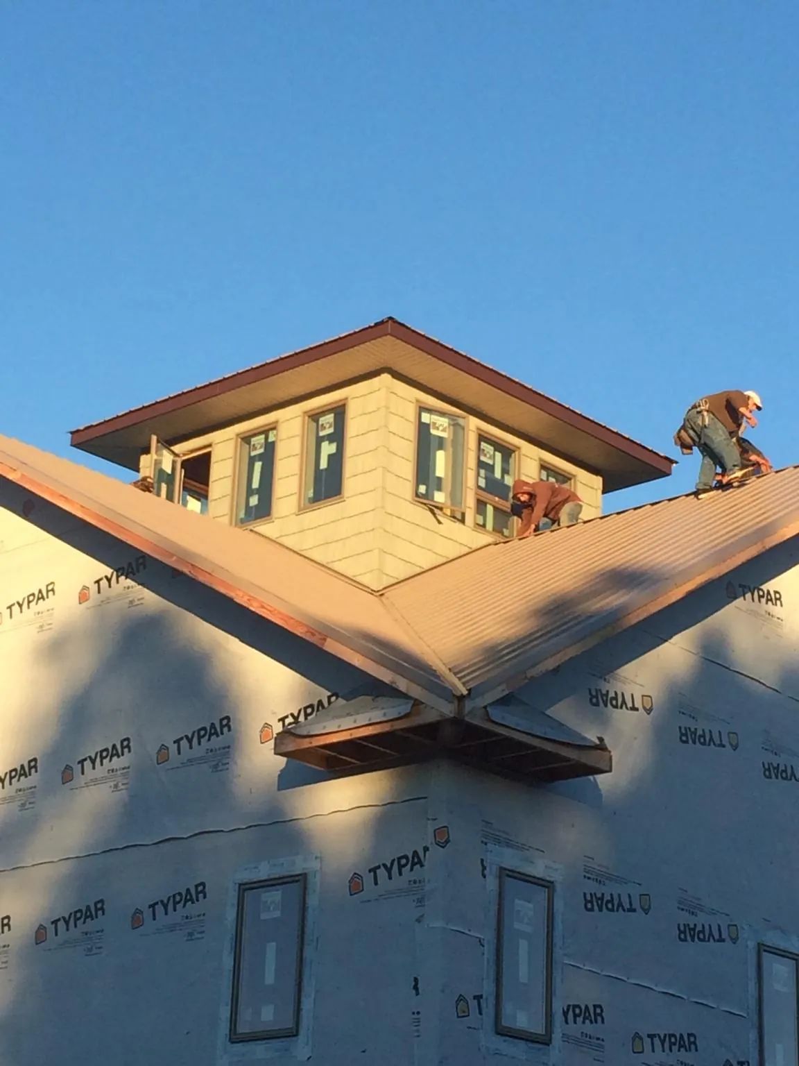 Roofers working around a rooftop cupola on a new metal roof at sunset — Roof Waterproofing in Whitestown by Roofing Brothers